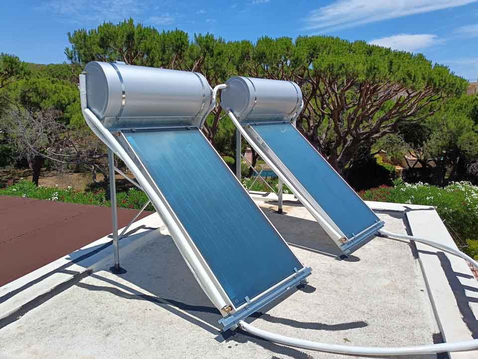 An installed hot solar water system on a tile roof with a white tank and two black panels